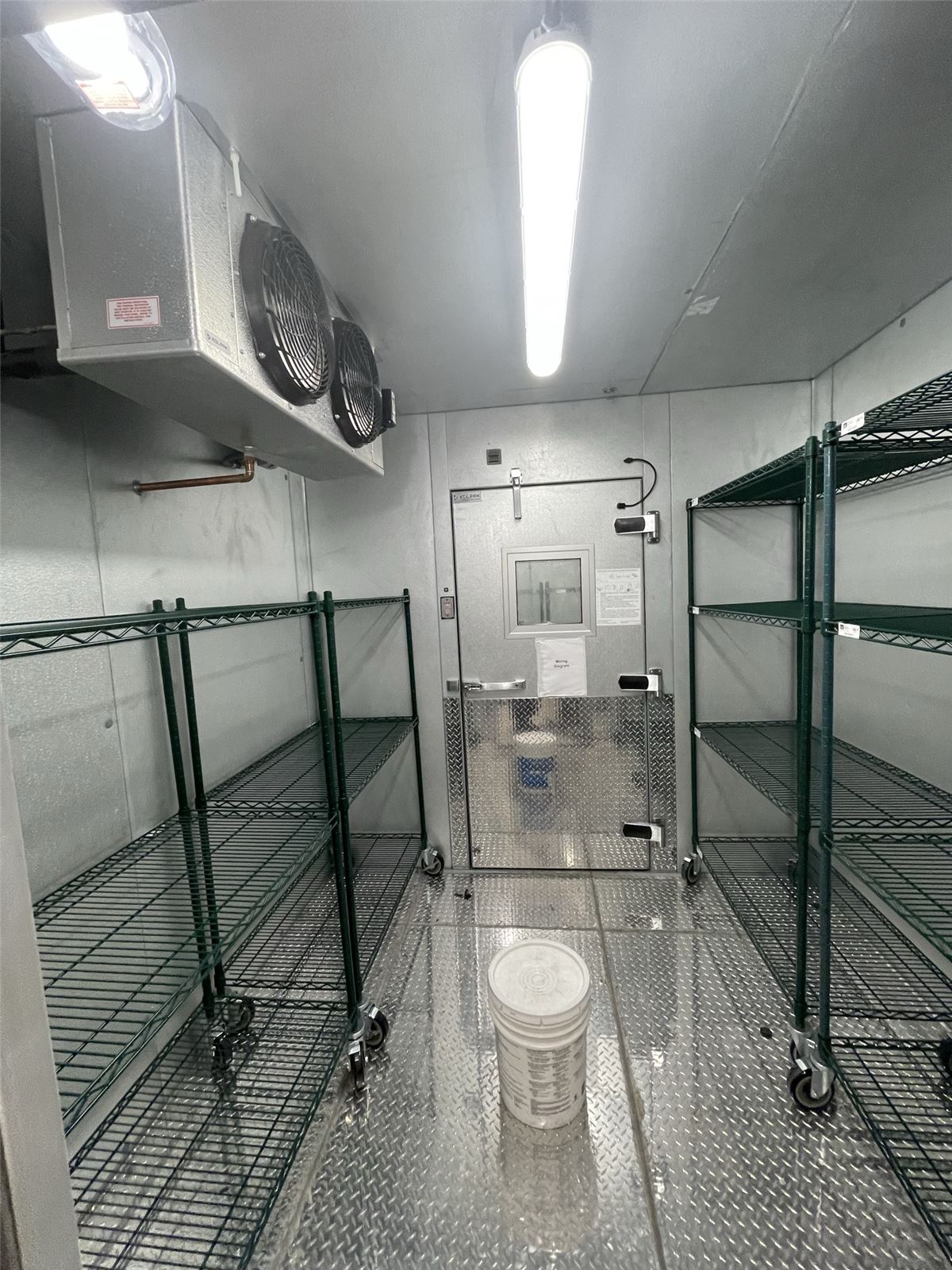 Inside a commercial walk-in cooler with wire shelving and evaporator unit
